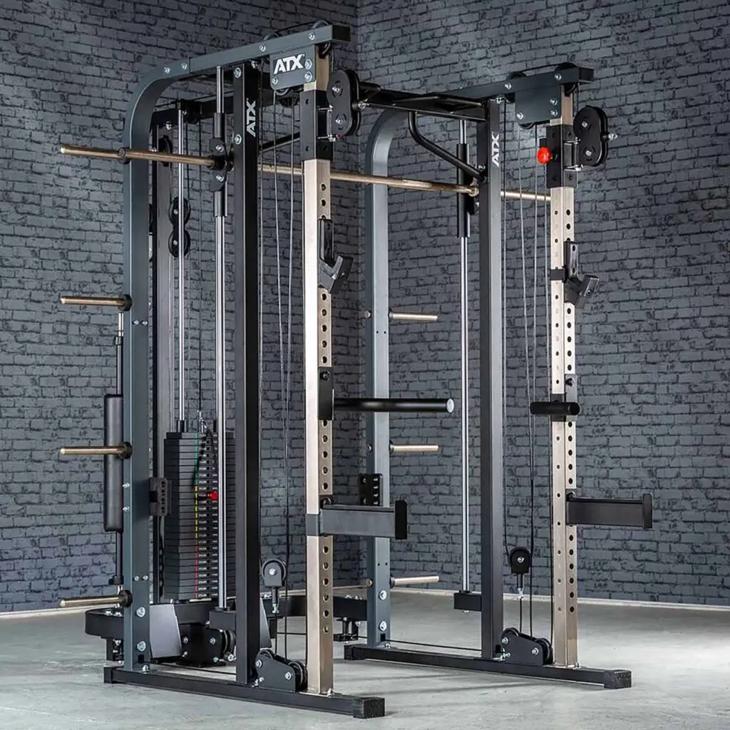 A large, multi-functional gym machine with weight stacks, pulleys, and bars for various strength exercises. Its set against a gray brick wall in a clean, spacious room with a concrete floor.