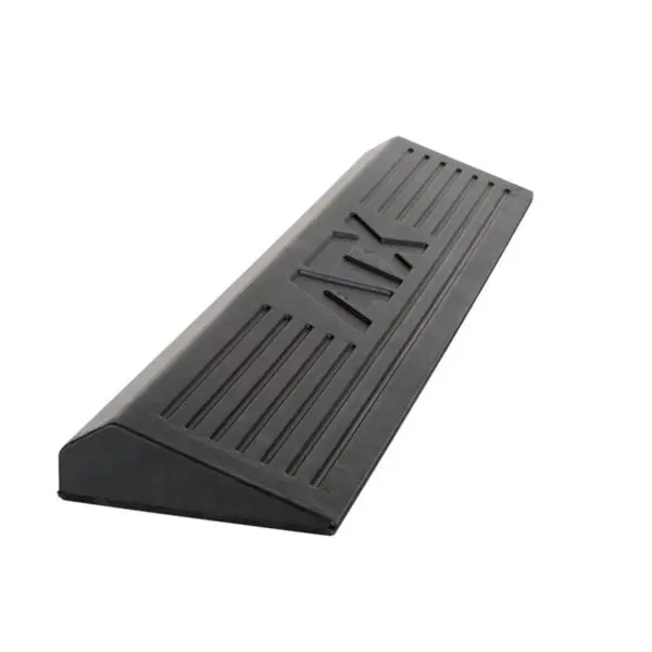 The ATX® Calf Block is a black rubber doorstop featuring horizontal grooves, a sloped design, and a textured surface for excellent grip and secure placement.