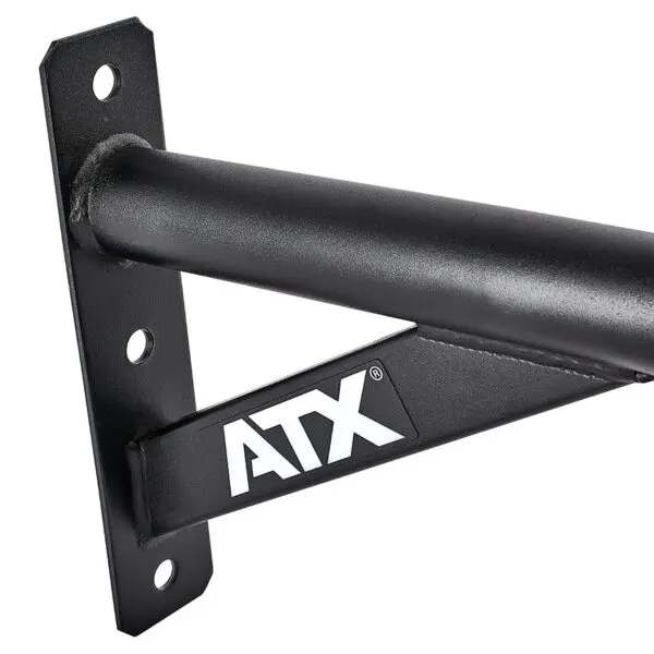 Close-up of a black metal ATX® Chin Up Bar Wall Mounted, showing a triangular support and white ATX letters. The bar is fixed to a flat vertical surface with bolt holes for mounting.