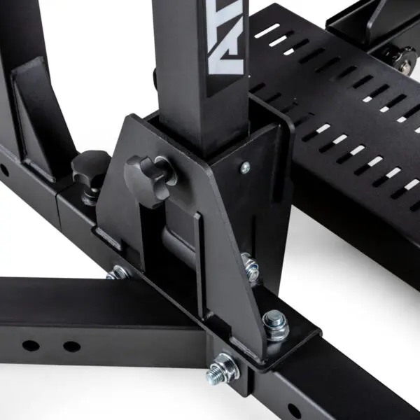 Close-up of a black metal bracket with bolts, part of the ATX® Competition Combo Rack. The bracket has an adjustable knob and is attached to a base with slotted details, showcasing industrial design elements.

.