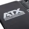 Close-up of a black exercise bench with the ATX® Competition Combo Rack logo in white, with parts of the metal support structure visible in the background.
