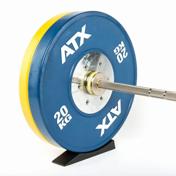 Close-up of a barbell with a blue 20 kg ATX weight plate mounted on a stand, ready for action. A yellow weight is partially visible behind the blue plate. Beneath, an ATX® Deadlift Wedge steadies the setup, ensuring optimal positioning as the barbell rests horizontally.