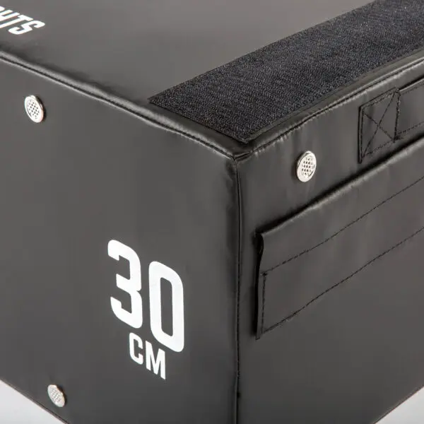The ATX® 30 cm Soft Drop Block features a close-up of its black surface with reinforced corners and Velcro straps for stability, offering a durable option for workouts.