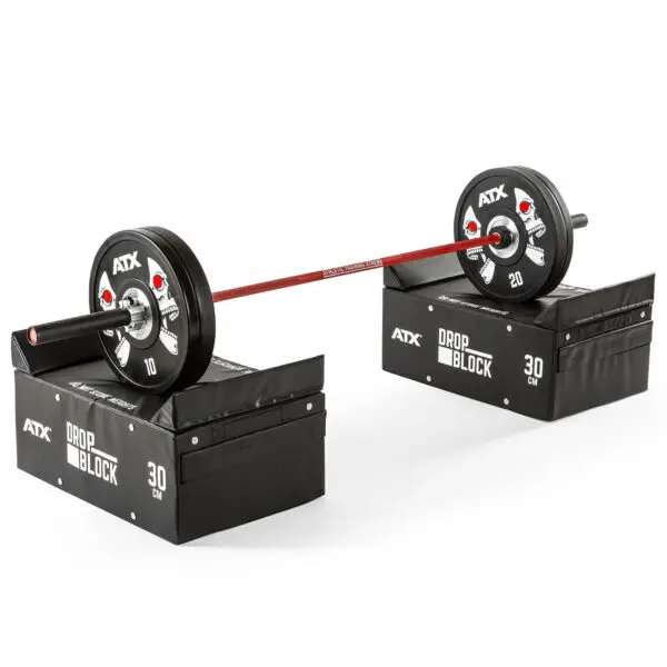 A barbell with 10 and 20 weights on each end is balanced on two ATX® 30 cm Soft Drop Blocks, set against a plain white background.