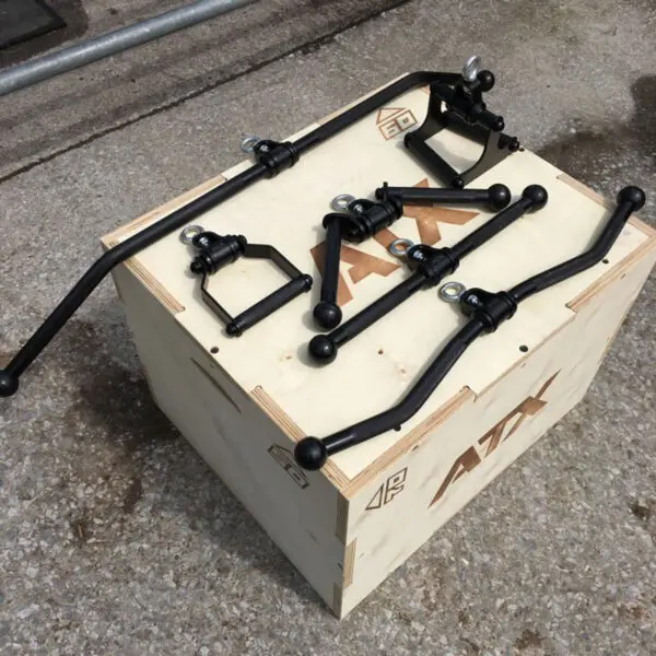 A set of ATX® Lat Bar Blackline stabilizer bars and brackets is displayed on a wooden crate marked with ATK logo. The sleek black metal finish contrasts with the rustic crate and concrete backdrop.