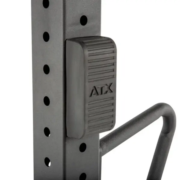 Close-up of an ATX® Jammer Arms adjustable safety stop on a gym rack, featuring a textured handle and multiple holes for height adjustment.
