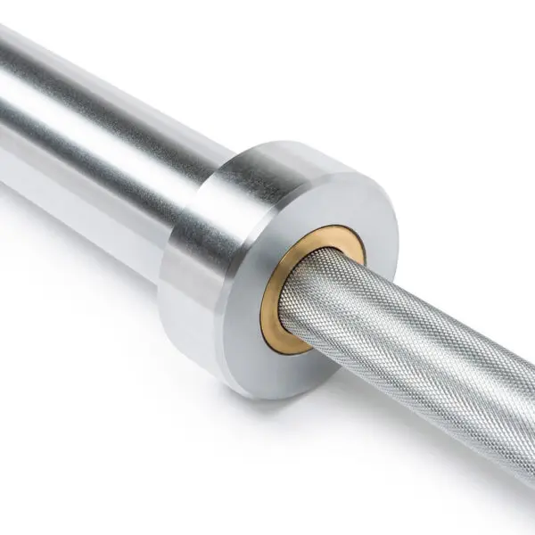 A close-up of the ATX® Competition Olympic Weightlifting Barbell displays its knurled grip and smooth rotating sleeve with a brass bushing. The metal surface reflects light, highlighting its polished finish.