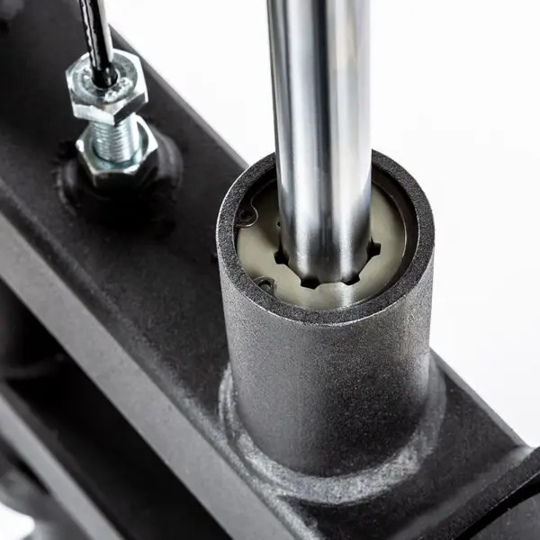 Close-up of a shiny cylindrical metal rod inserted into an ATX® Lat Option 650 Plate Loaded component, with a threaded bolt and wire nearby, contrasting the matte black parts.