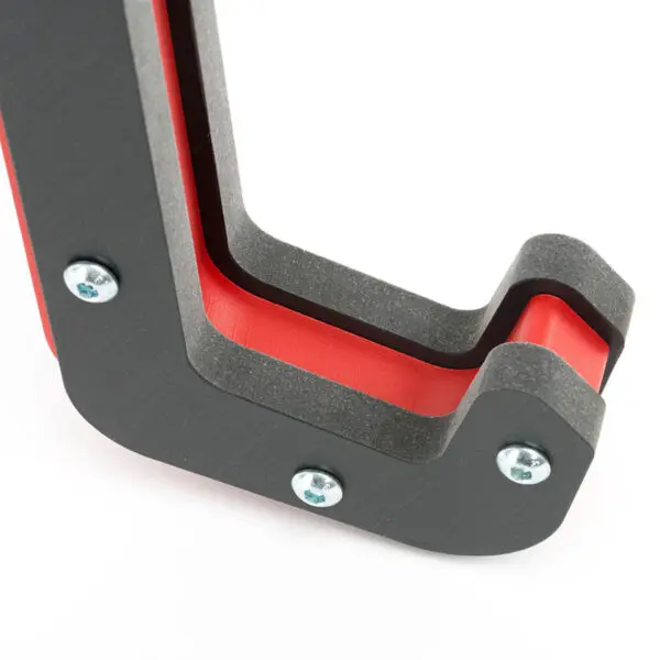Close-up of an ATX® Mono Lift, showcasing its red and black layered structure with three metal screws, curved edges, and a modular design that suggests both functional and decorative use.