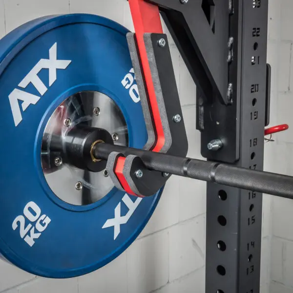 A close-up shows a blue 20 kg weight plate on the ATX® Mono Lift, securely attached to a barbell rack against a white brick wall.