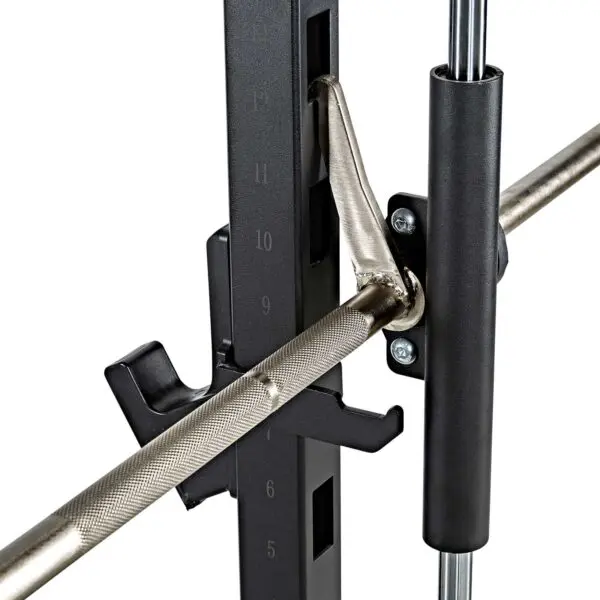Close-up of the ATX® Smith Machine System Plate Loaded, featuring a barbell with safety catches and knurled grip, resting on a rack with measurement markers for weightlifting or gym use.