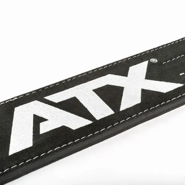 Close-up of the ATX® Lever Suede Power Belt in black suede with white stitching, prominently displaying the bold white letters "ATX" on it against a plain, light-colored background.