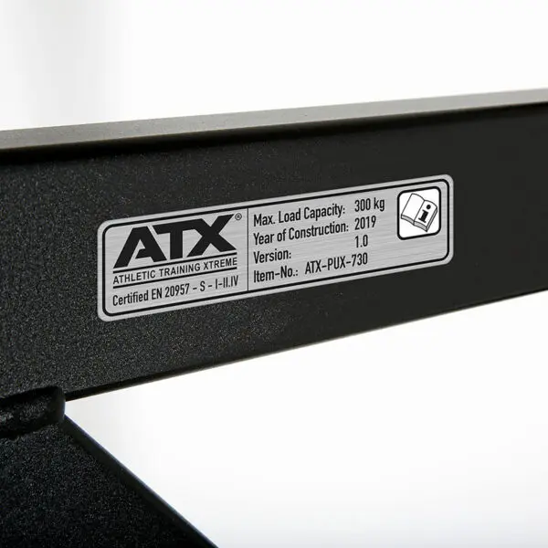 Close-up of the label on the ATX® Gladiator Chin Up Bar detailing: Max Load Capacity - 300 kg, Year of Construction - 2019, Version - 1.0, Item No. - ATX-PUX-730, Certified EN 20957. Branding reads ATX Athletic Training Xtreme.