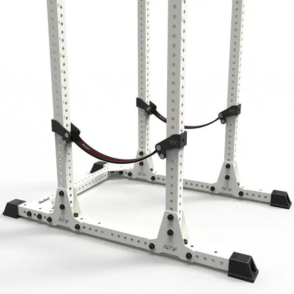 The ATX® Safety Strap System is a white metal squat rack with black foot stabilizers, adjustable safety straps, multiple adjustment holes, and the ATX logo on both the frame and straps, all set against a white background.