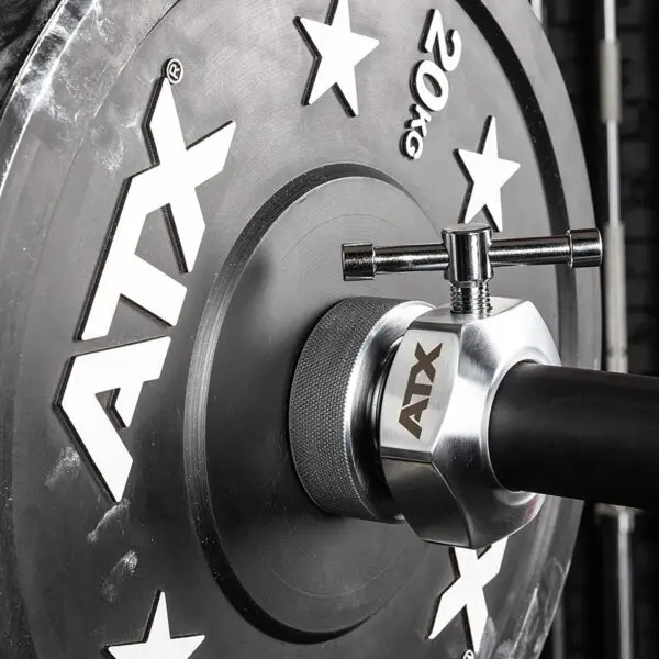 Close-up of a 20 kg weight plate loaded on a barbell, secured with an ATX® Competition Collars Short IPF. The plate displays ATX branding and star designs, with the textured grip area visible on the barbell.