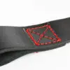 The ATX® Bulls Strongman Yoke features a close-up of its black leather strap with striking red stitching in a square-X pattern, reminiscent of robust strongman gear. The detailed stitching contrasts beautifully against the smooth leather, all set on a plain white background.