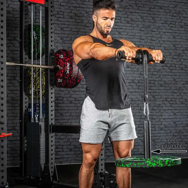 A man in a gym uses an ATX® Wrist Forearm Trainer to lift a weighted plate with a rope. He is wearing a black tank top and gray shorts, standing in front of a wall of gym equipment.