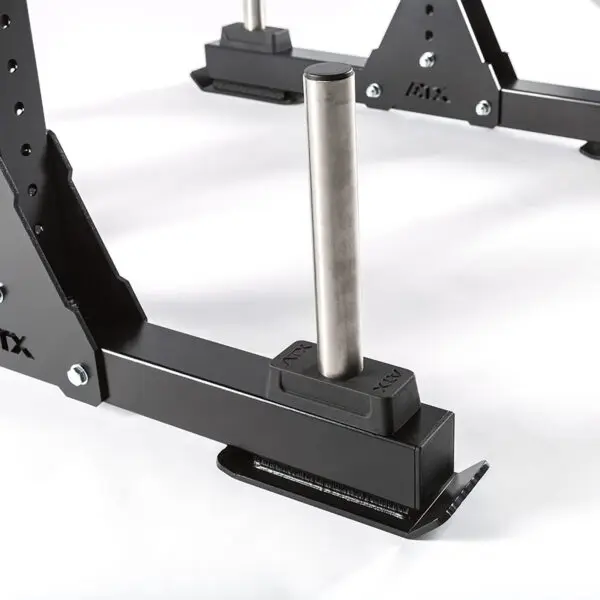 Close-up of a black metal gym part, showcasing a cylindrical steel peg on a rectangular base with a support structure, resembling components from the discontinued ATX® Bulls Strongman Yoke. Ideal for plate storage or weightlifting rack usage.