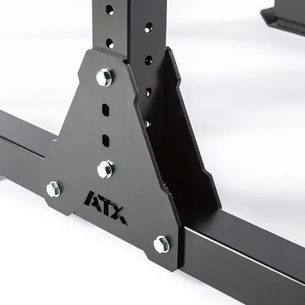 Close-up of a black metal frame with multiple bolts and perforated holes, labeled ATX® Bulls Strongman Yoke DISCONTINUED at the base. The structure resembles gym equipment like a yoke or squat rack, providing robust support against a plain white background.