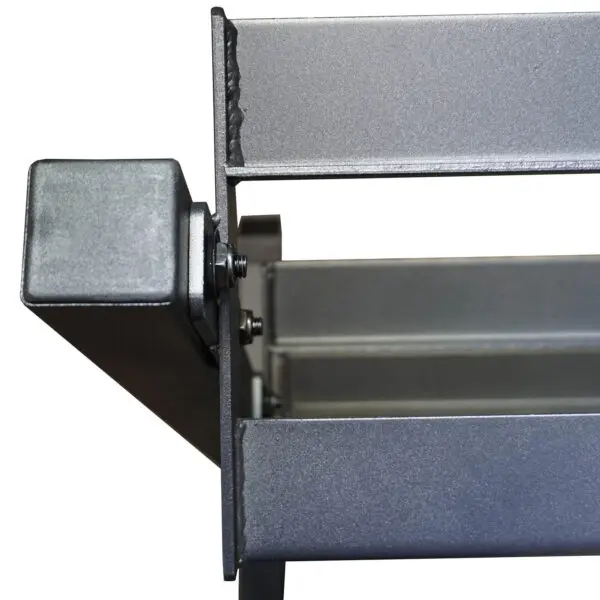 The Power Maxx Compact Hex Dumbbell Rack features a metallic rectangular bracket with a textured finish, bolts, and angular edges. An open section reveals its steel-gray surface with a light sheen, indicating sturdy construction.
