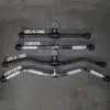 A top-down view showcases three black Power Maxx Wide Row Handles with ribbed grips on a dark surface. Two are labeled ATX-G-7003 and CGRVSTR, while one is slightly curved and labeled ATX-G-7002 and CGRVZCRL.