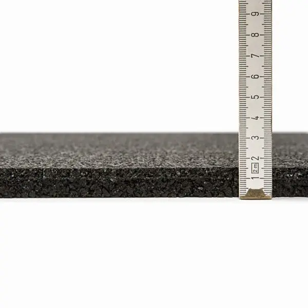 A close-up of the GymFloor® 15mm 1m x 1m Black slab features a ruler on the right side, showcasing its approximate thickness of 1.5 centimeters with a textured surface.