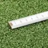 A GymFloor® RTS Turf 50x50@20mm patch has a tape measure in centimeters on it, with the green turf contrasting against the white tape for clear visibility of its markings.
