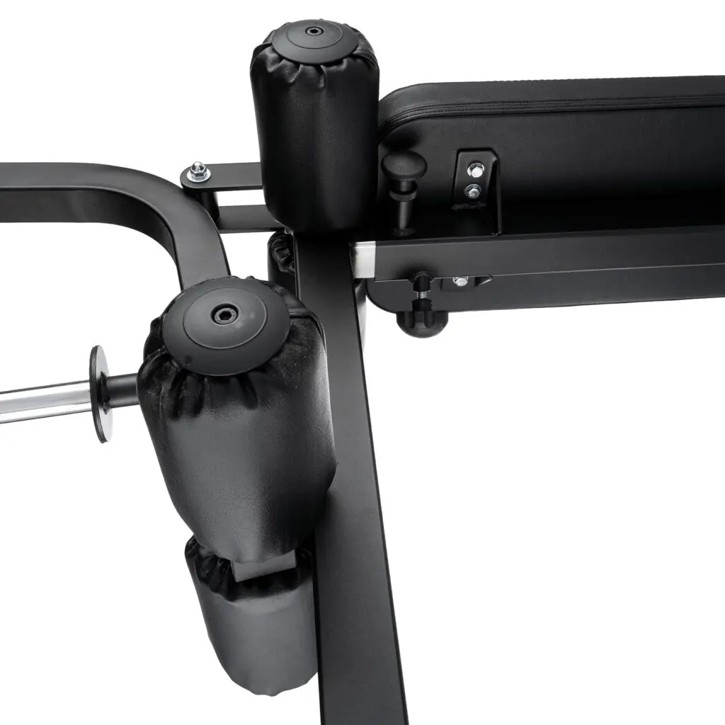 Close-up of the Ironmaster Leg Lift PRO, highlighting its padded rollers and bench. The focus is on the padding and robust metal frame that emphasize its construction and design features.
