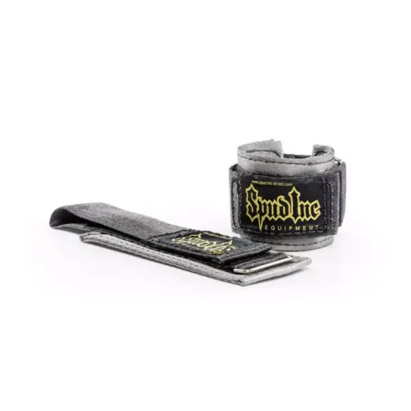The Spud Choker Wrist Wraps feature a gray design with black and yellow Spud Inc. Equipment branding. The wrist wrap is rolled into a cylinder, while the matching strap is laid flat to highlight its texture and design.