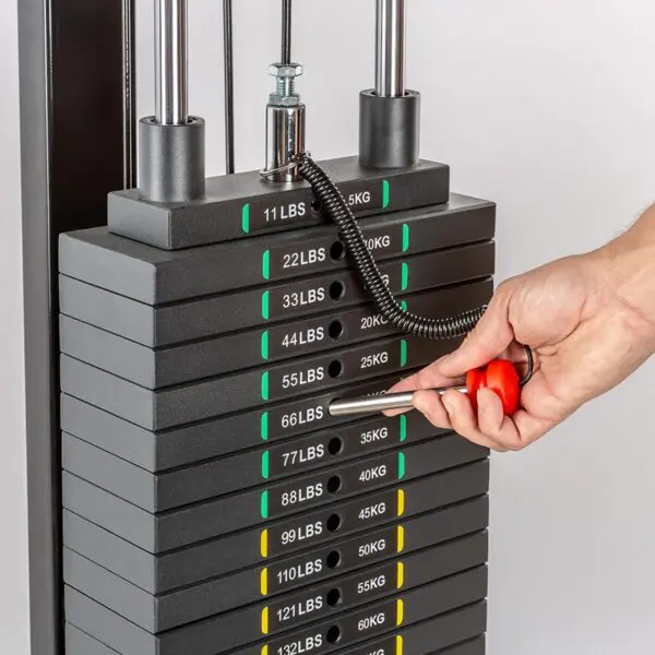 A hand uses the Magnetic 10mm Weight Stack Pin 140mm to adjust a stacked weight machine with markings from 11 lbs (5 kg) to 132 lbs (60 kg). The pin is set at 55 lbs (25 kg), and the weights are labeled in both pounds and kilograms.