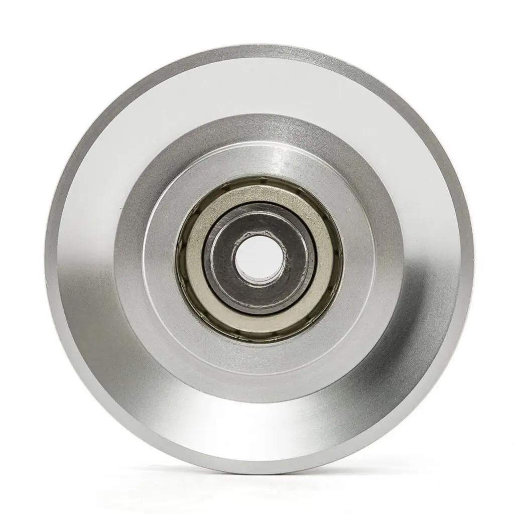Close-up of a shiny, metallic wheel or disc with a central ball bearing, shown from a top-down view against a white background.