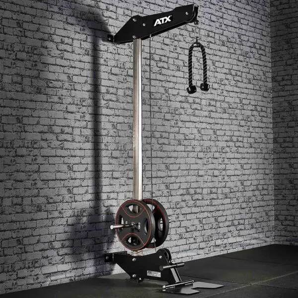 The ATX® Wall Mounted Lat Pulldown boasts a sleek black metal frame, weight plates, and a double-handle grip. It is ideally positioned against a textured gray brick wall in a gym setting, providing both functionality and style for an intense workout experience.