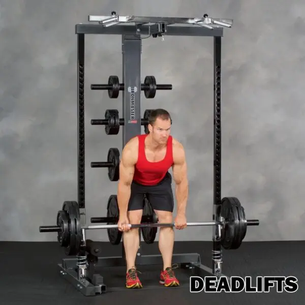 A person in a red tank top and black shorts performs a deadlift with the Ironmaster IM2000 Self-Spotting Smith Machine on a weightlifting rack. The word DEADLIFTS is written in bold at the bottom right.
