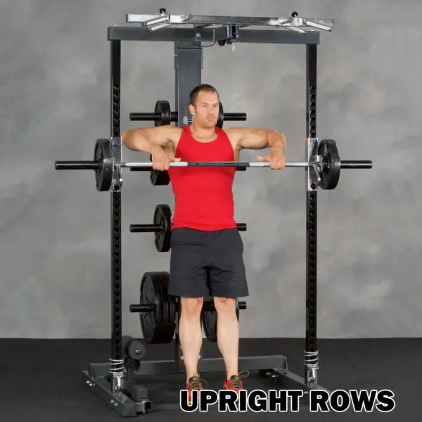 A person in a red tank top and black shorts does upright rows in a gym using the Ironmaster IM2000 Self-Spotting Smith Machine, lifting the barbell to chest height. Text reads, UPRIGHT ROWS.