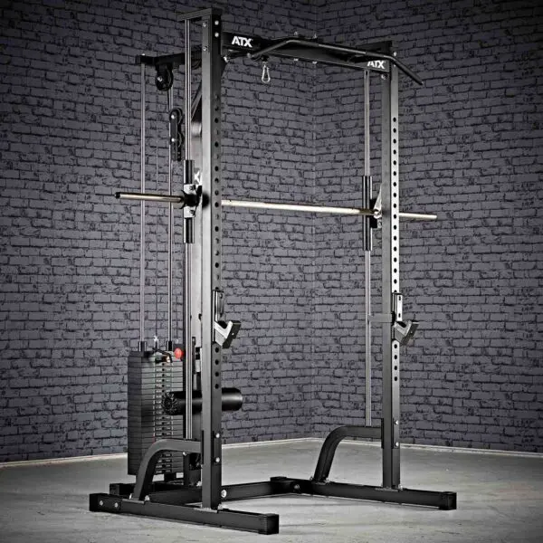 The ATX® Smith Machine System Stack Weight 115 kg, in black, is set up in a room with a textured gray brick wall. It features a pulley system, a barbell, adjustable safety bars, and various attachment points for workouts.