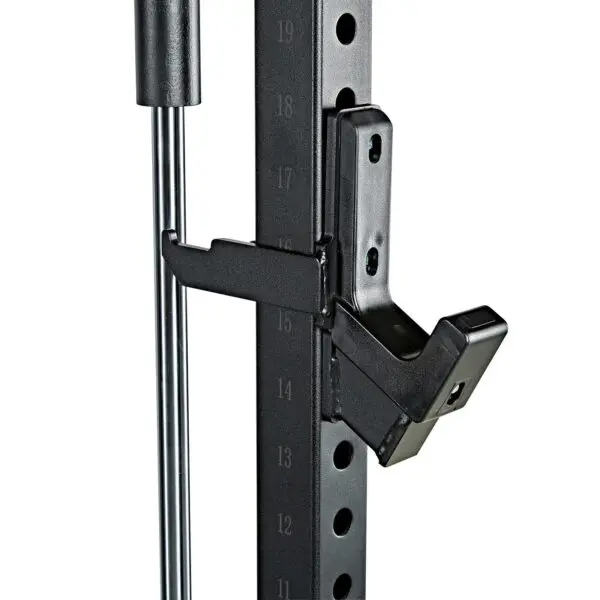 Close-up of the ATX® Smith Machine System Stack Weight 115 kg, featuring a numbered height adjustment system and a black metal safety hook attached for barbell support. Vertical silver bars are visible near the adjuster.