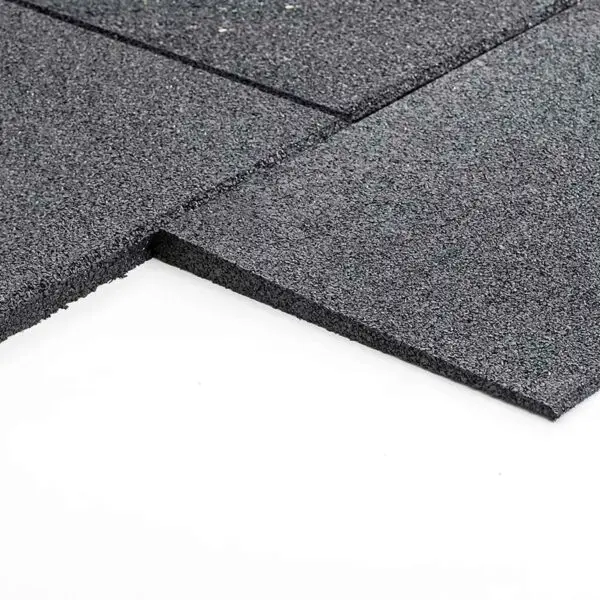 Close-up of GymFloor RTS 50x50@20mm System, featuring square black rubber tiles with a textured, granulated surface, arranged on a white background and slightly stacked to display their thickness.