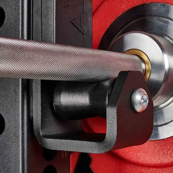 Close-up of the ATX® Roller J-Hooks Universal holding a barbell with a red weight plate in the background. The textured grip and round shape of the plate are visible, along with a black metal holder and shiny bolt.