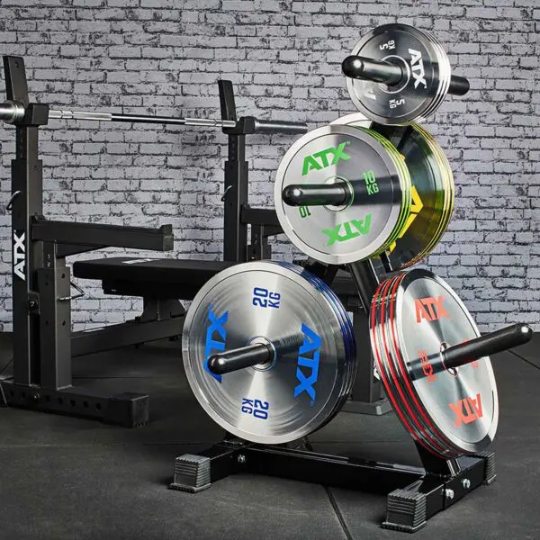 A gym setup with a weight bench and rack displaying ATX® 25kg Chrome Powerlifting Single Plates, against a brick wall backdrop and black gym matting on the floor.