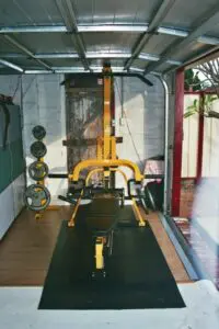 Seans Powertec Leverage Gym in his garage with weigh plates next to it.