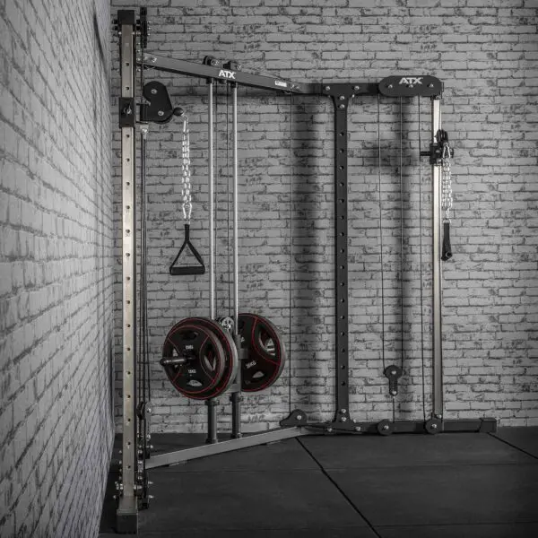 The ATX® Cable Crossover Plate Loaded, a discontinued wall-mounted gym machine with two cable handles and weight plates, is set against a brick wall on a black mat, enhancing the minimalist industrial vibe of the room.