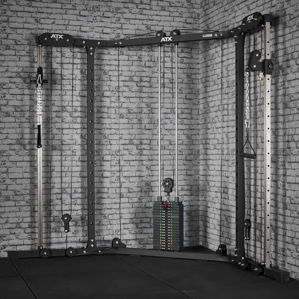 A home gym setup featuring the ATX® Cable Crossover Weight Stack 90 kg against a brick wall, equipped with adjustable pulleys for versatile upper body exercises, and a floor covered in black foam tiles.