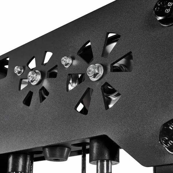Close-up of a black mechanical component from a cable station, featuring two circular cutouts with geometric designs. Visible bolts and screws enhance its industrial appearance. The plain background highlights the detailed metalwork, emphasizing the precision typical of cable weight machines.