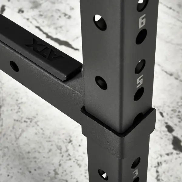 Close-up of the ATX® Power Rack 770 XL SET, featuring numbered holes for height adjustment and a matte finish. The ATX logo is visible, while the concrete floor beneath shows signs of use.