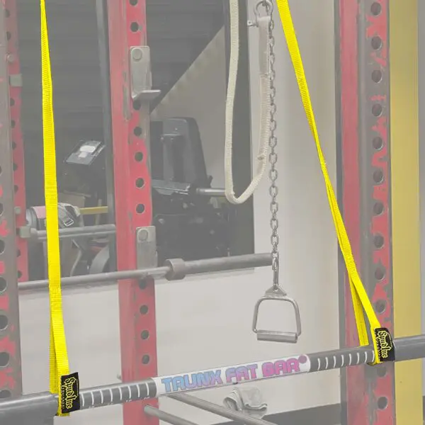 A gym setup featuring a Spud Pittsburgh Jammer with a Fat Bar on yellow straps in a red rack, plus a chain handle. Exercise equipment is visible in the background.