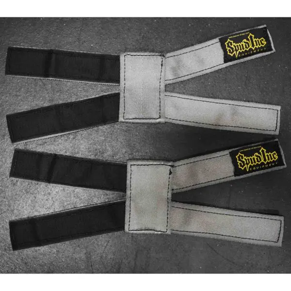 Two Spud Inc 5R Barbell Shields in gray and black with yellow branding on a dark surface, each featuring a loop and velcro closure for secure attachment.