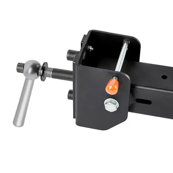 Close-up of the ATX® Belt Squat Option showing a black metal lock mechanism with a silver handle, visible nut, and bolt. An orange safety indicator is on the side, designed to ensure trailer security when hitched to vehicles.