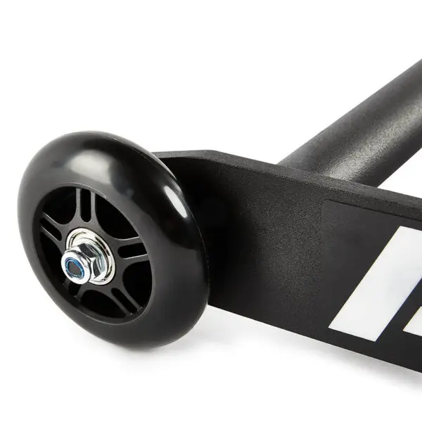 Close-up of a black ATX® Glute Ham Roller wheel attached to a sleek metal frame, featuring a white graphic design. The wheel, reminiscent of the product itself, has visible spokes and a shiny central bolt.