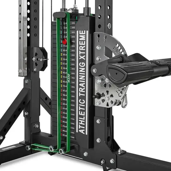 A close-up of a weight stack from an ATX® Trinity Tower 135 kg machine shows multiple weight plates, adjustment pins, and a cable system designed for resistance training and strength exercises.