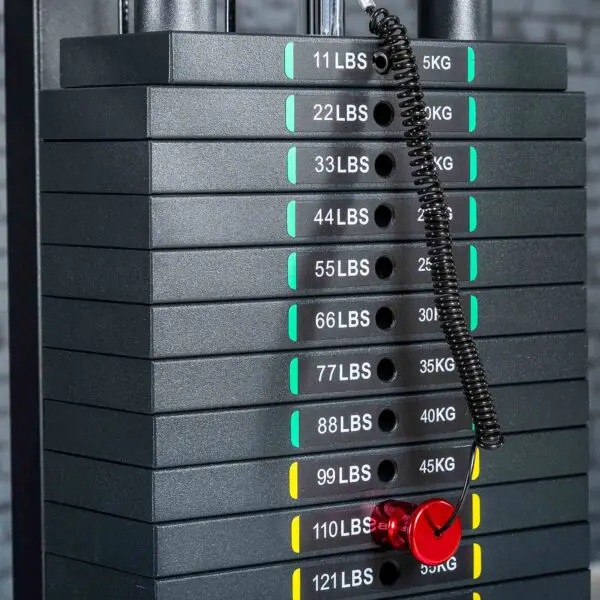 A stack of weight plates on a gym machine features Weight Stack Stickers KG/LBS. A red pin is inserted in the 77 lbs (35 kg) slot, attached with a coiled black cord.